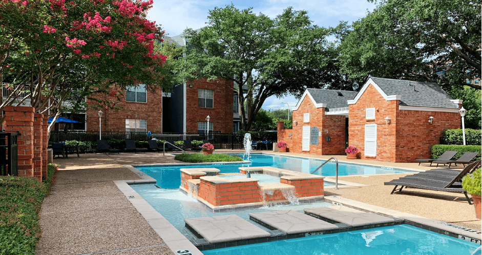 Luxury apartments with two swimming pools with fountain, poolside lounge chairs, and beautiful landscaping in Dallas
